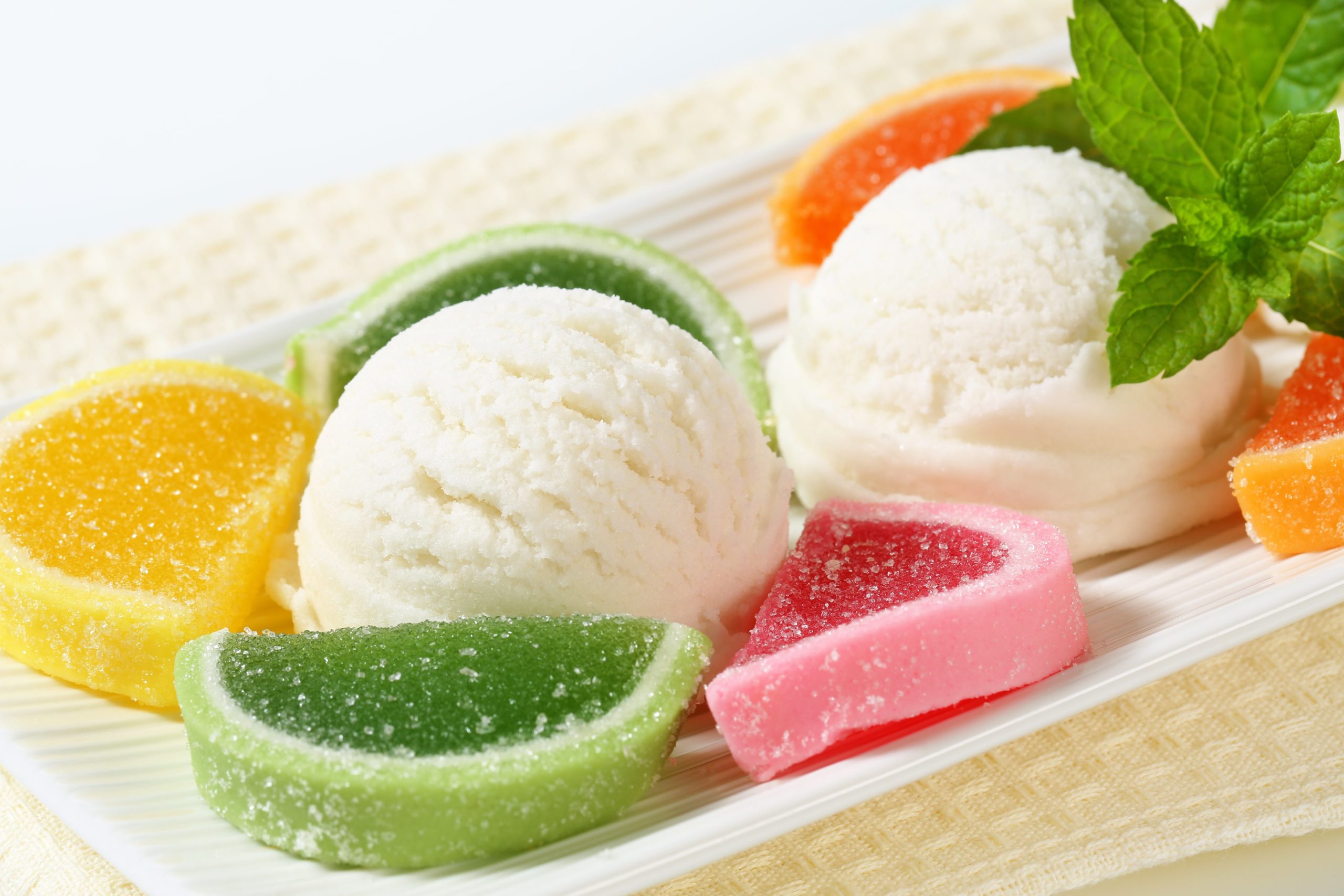 A white plate with ice cream and jelly slices on it