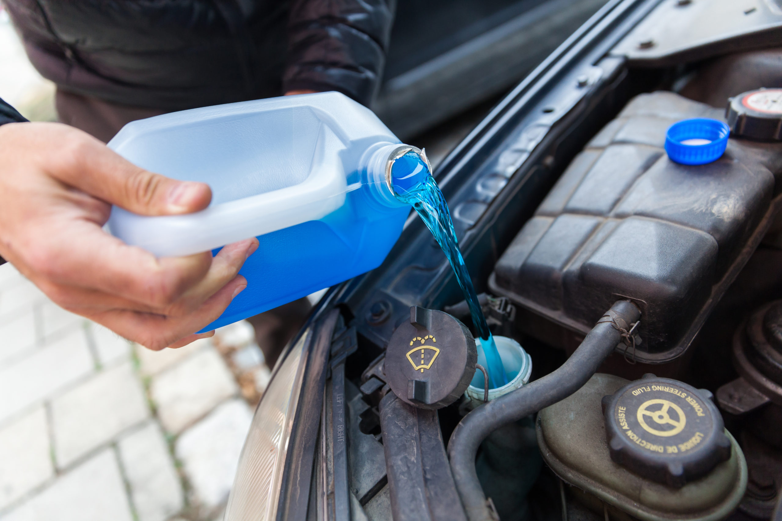 A bottle of blue liquid is being poured into a car
