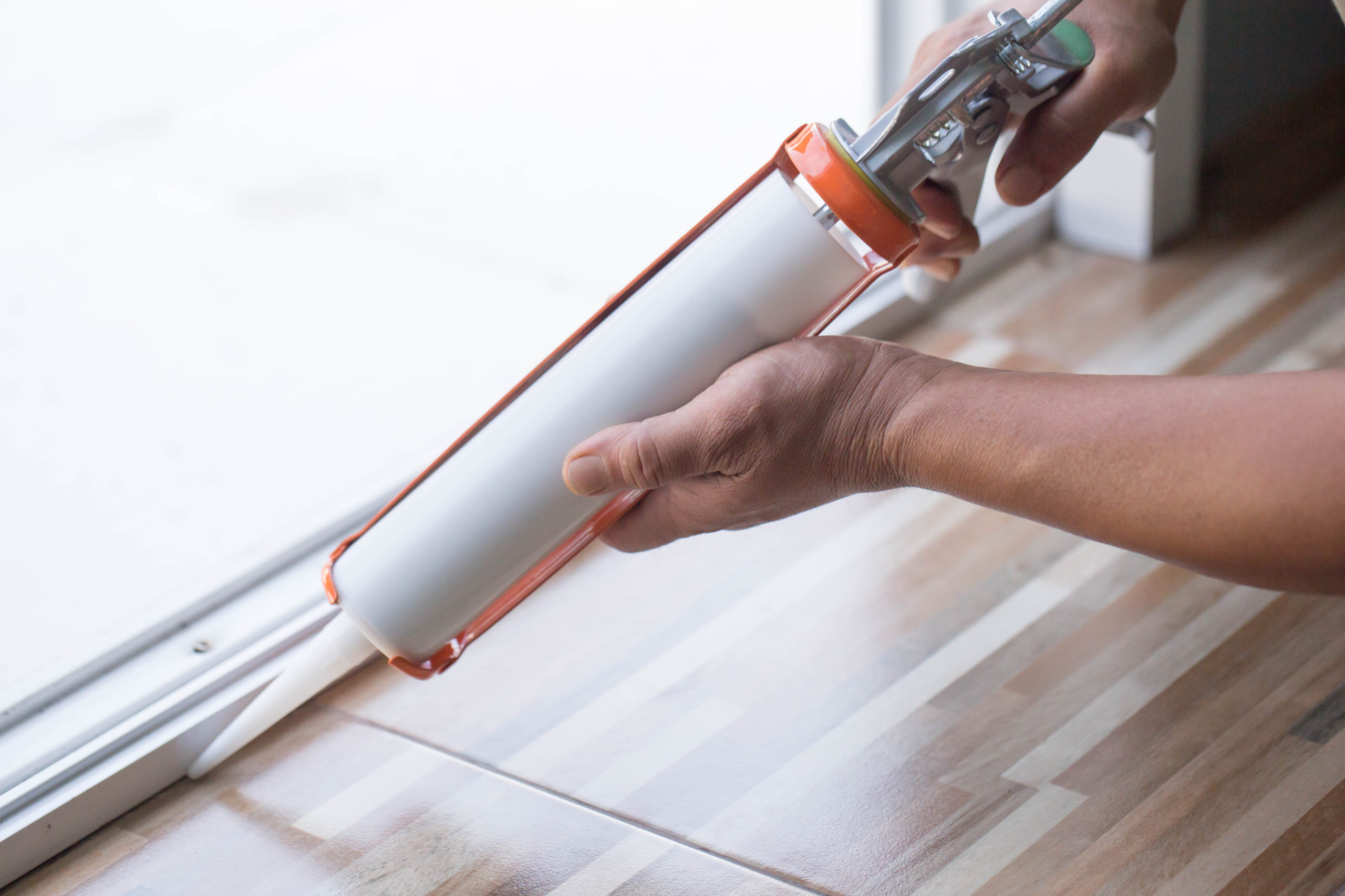 A man using a silicone adhesive with a glue gun.