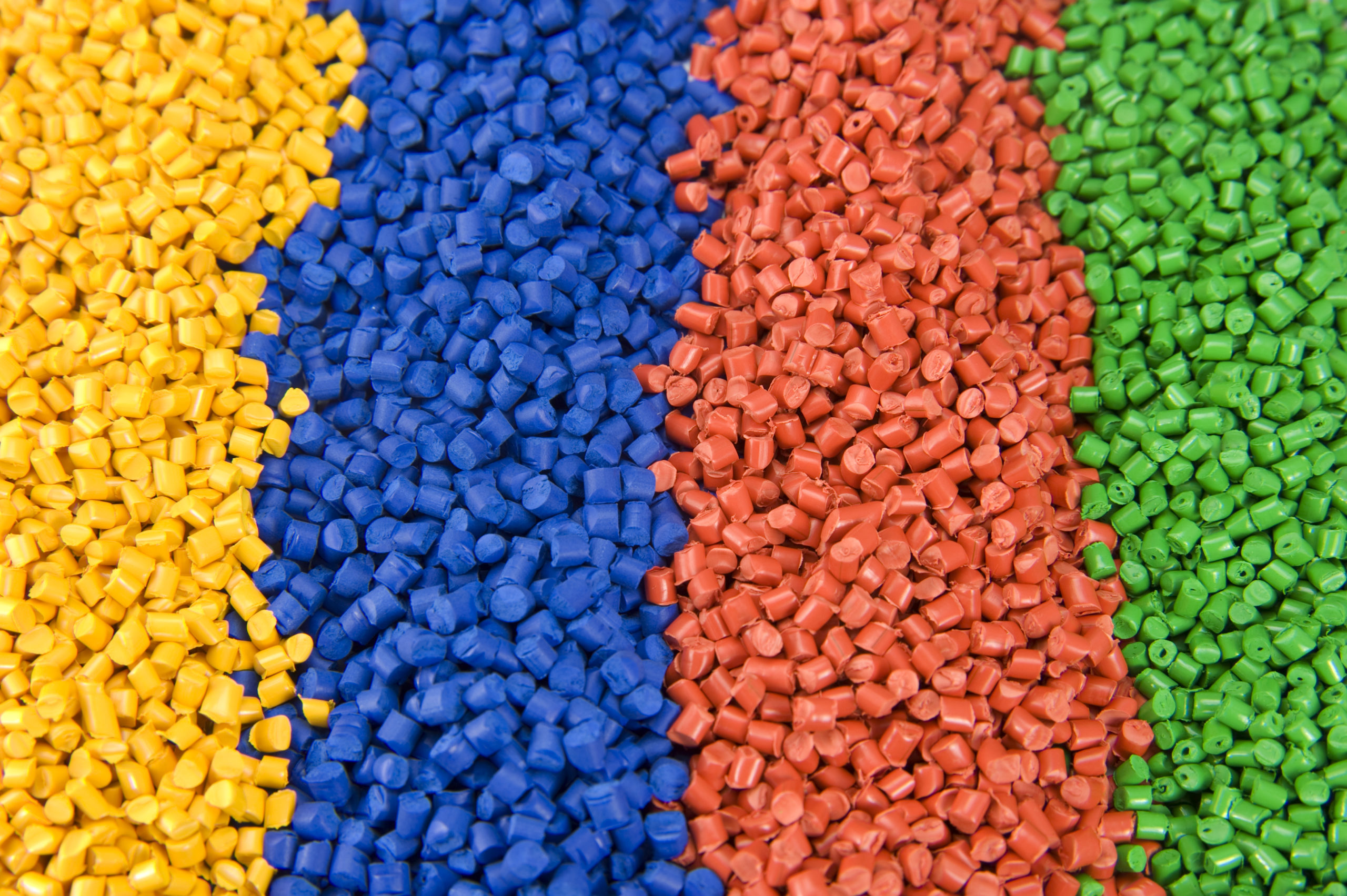 Plastic yellow, blue, red, and green polymer granules.