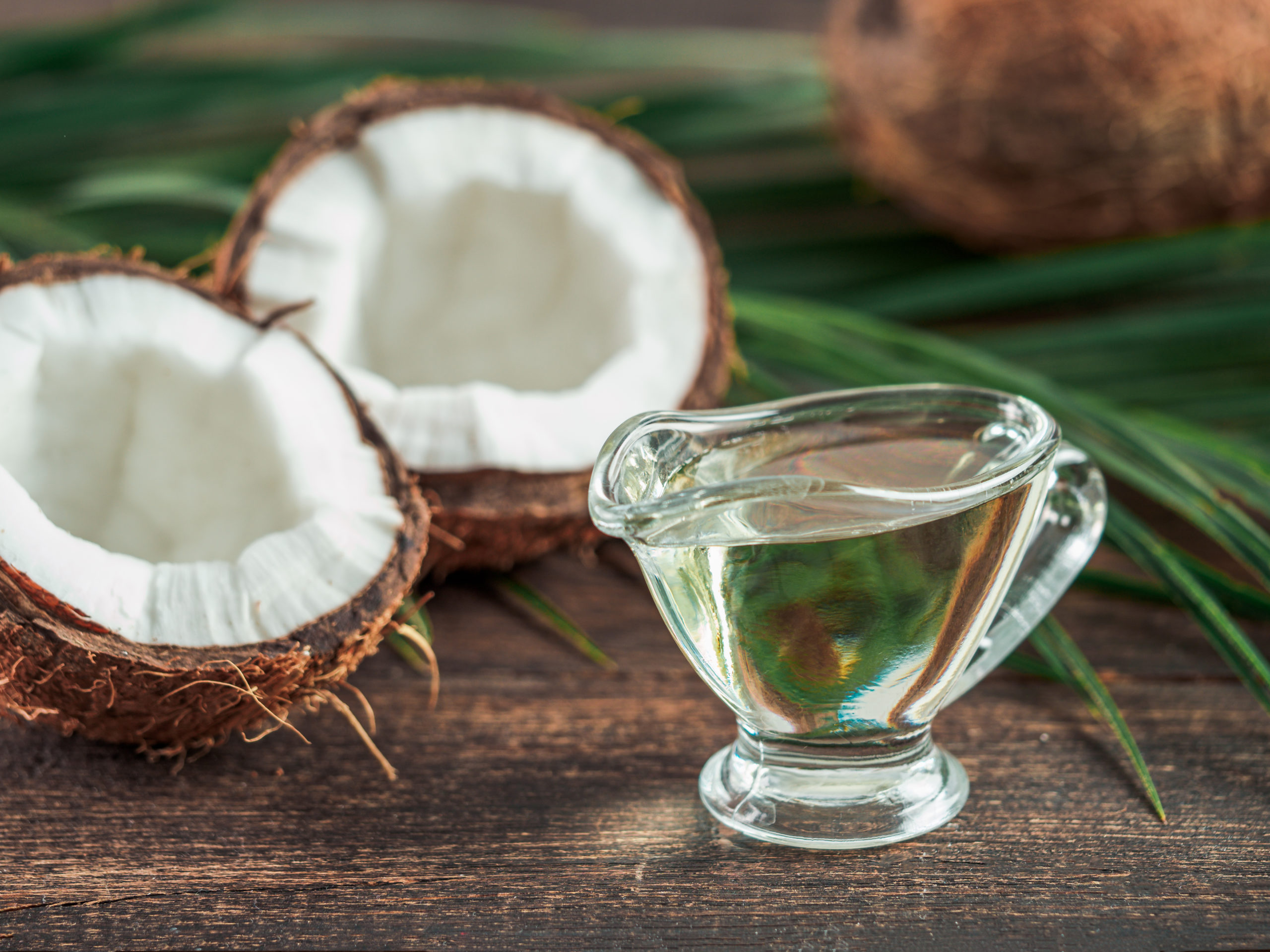 a glass of coconut oil sits on a wooden table