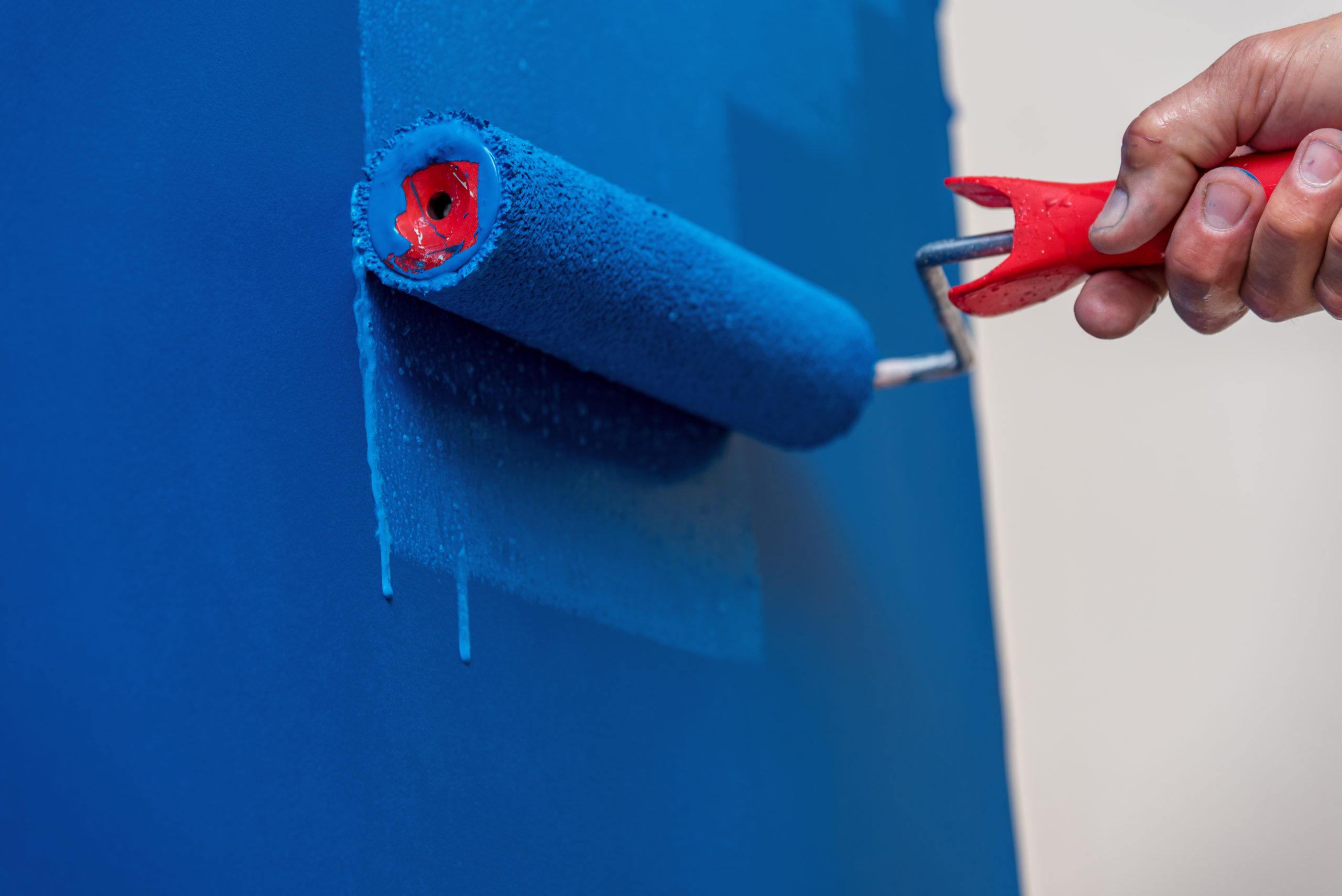 Decorators hand painting the wall blue with a roller.