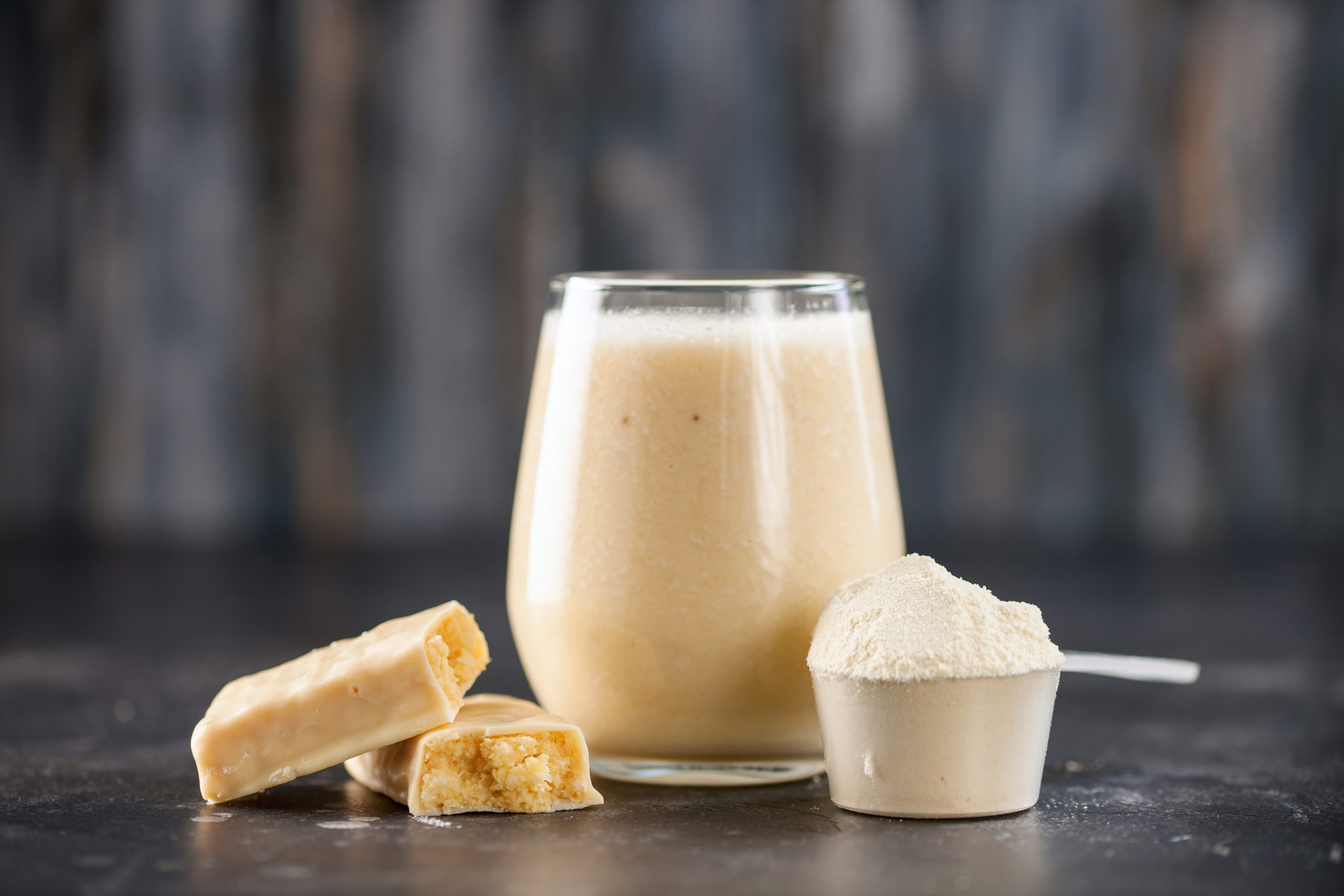 A scoop of protein power next to a drink in a glass cup