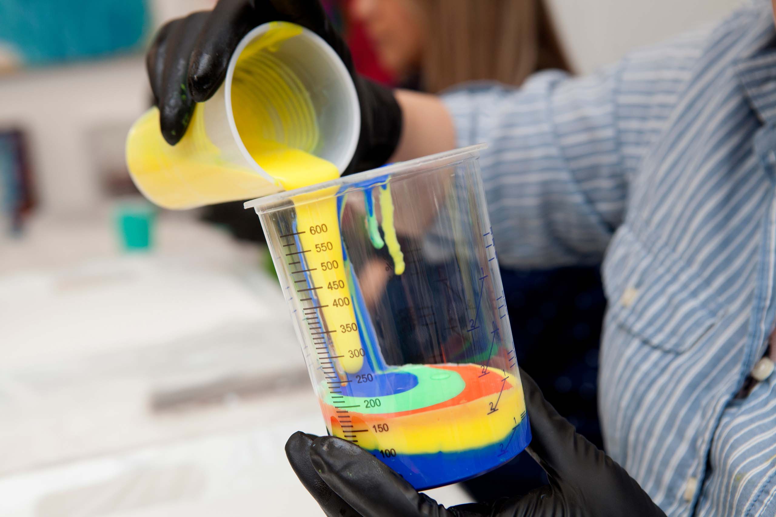 Pouring paint with surfactants in a lab beaker.