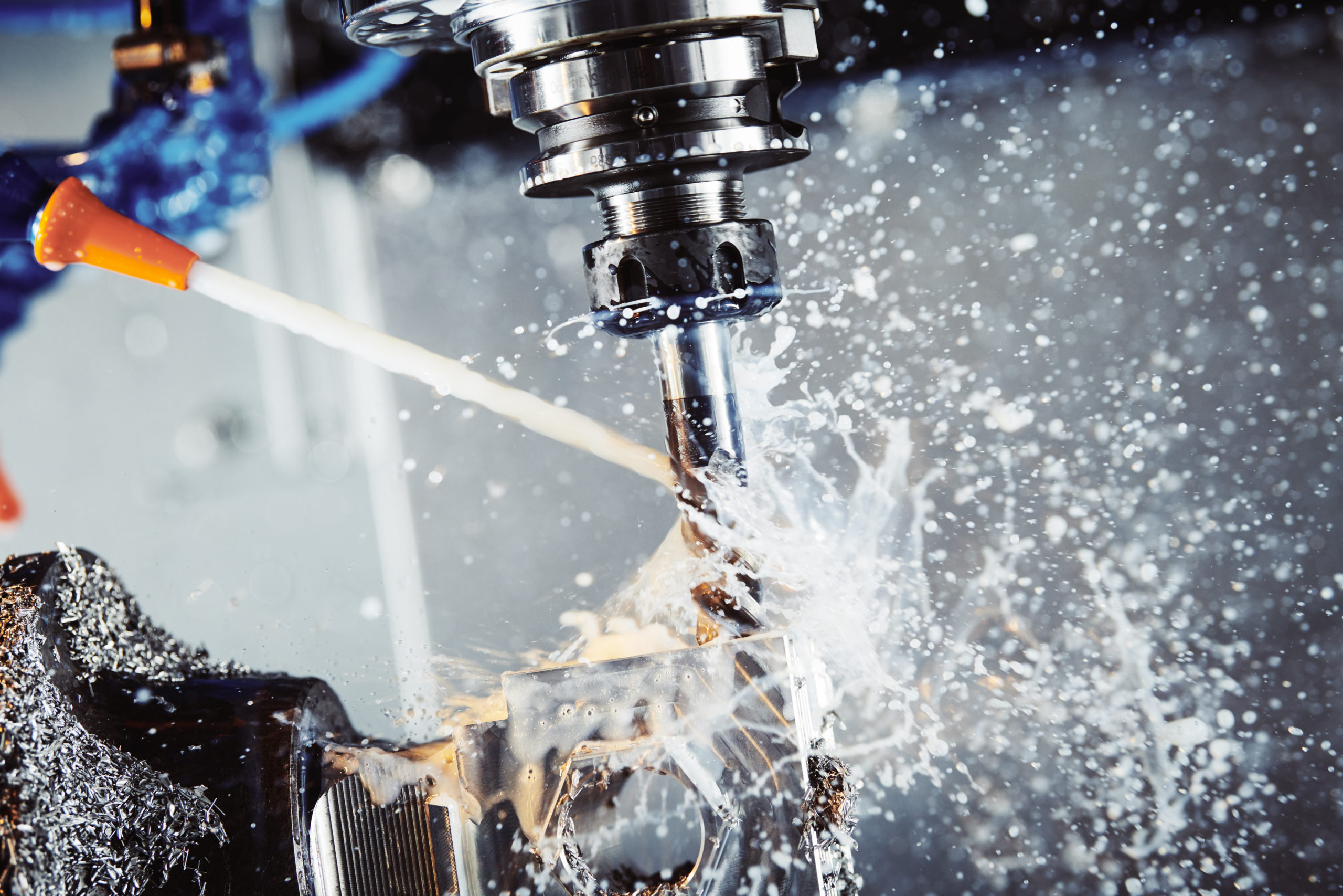 A machine is cutting a piece of metal with liquid coming out of it